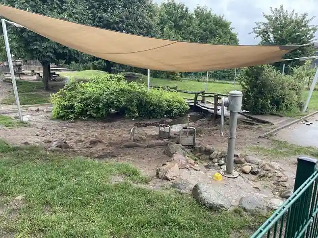 Foto von einem naturnahmen Wasserspielplatz mit Segel zum Sonnenschutz