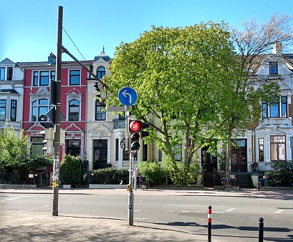 Ampel und Baum vor Häusern an Straßenkreuzung. 